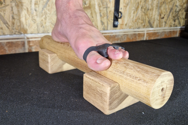 Persona realizando ejercicios de equilibrio sobre una barra de equilibrio para pies, demostrando cómo fortalecer la propiocepción con esta herramienta.